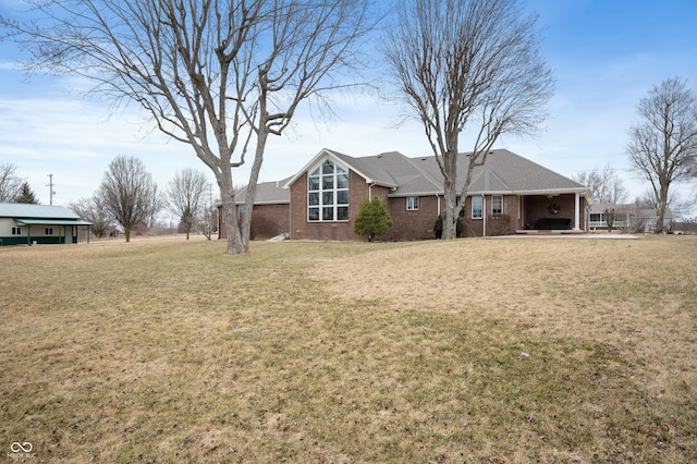 rear view of property featuring a lawn and brick siding