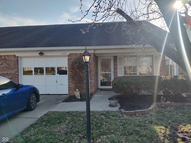 view of front of home with brick siding, driveway, a garage, and roof with shingles