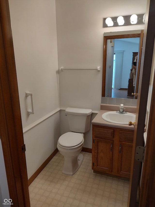 half bathroom featuring tile patterned floors, toilet, vanity, and baseboards