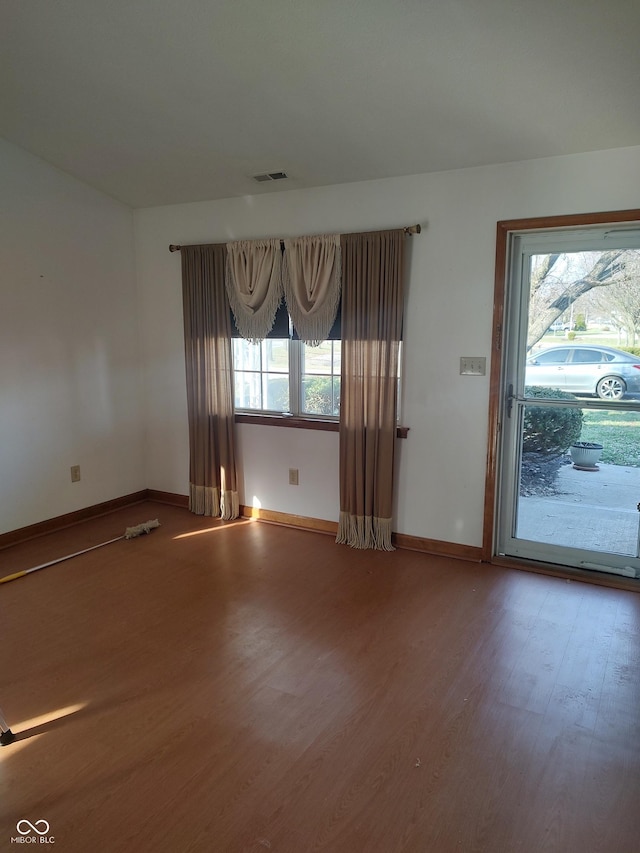 spare room featuring baseboards, plenty of natural light, and wood finished floors