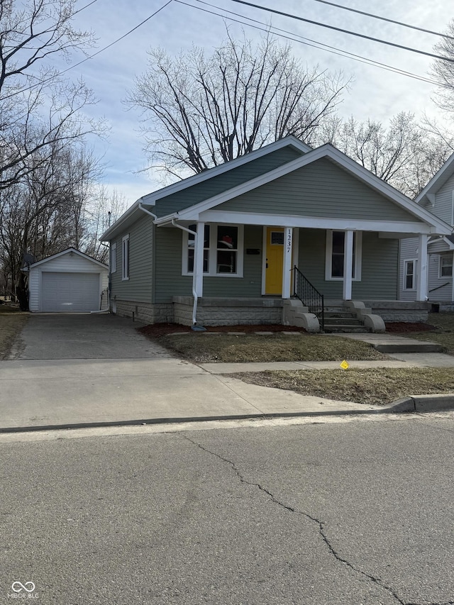 bungalow featuring covered porch, driveway, a detached garage, and an outdoor structure