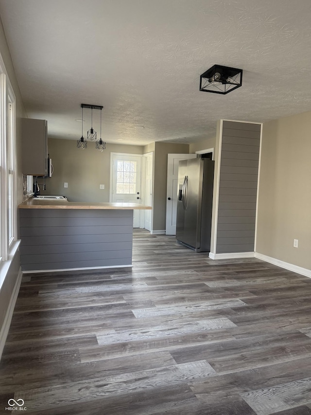 interior space featuring a textured ceiling, appliances with stainless steel finishes, a peninsula, and dark wood-style flooring