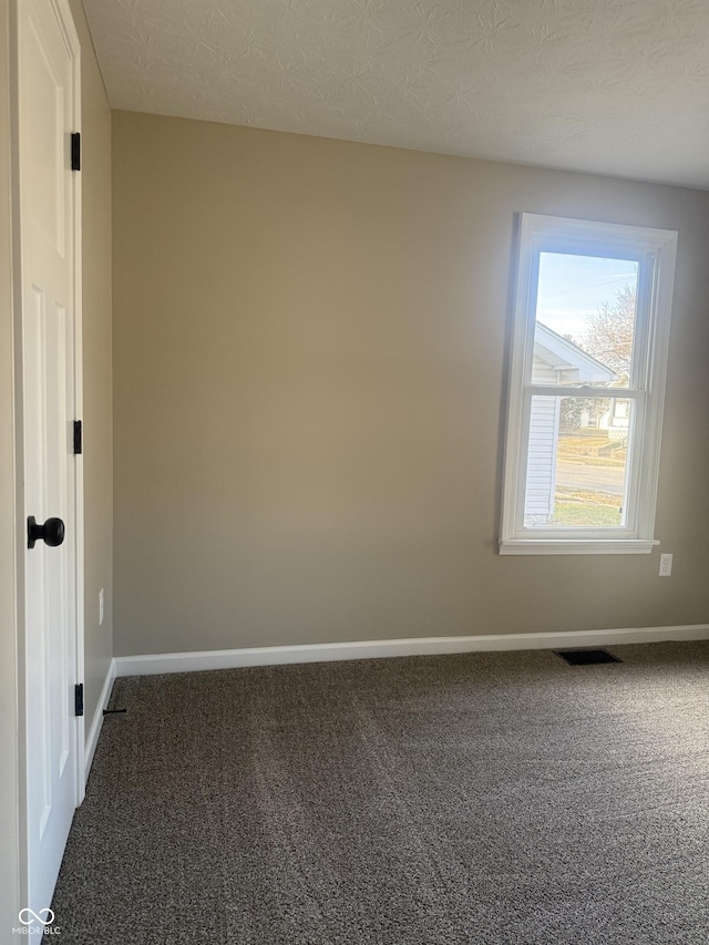 carpeted spare room with visible vents, a textured ceiling, and baseboards