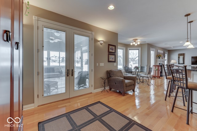 interior space featuring baseboards, light wood-style flooring, a fireplace, recessed lighting, and french doors