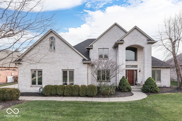 french country home with a front lawn, brick siding, and roof with shingles