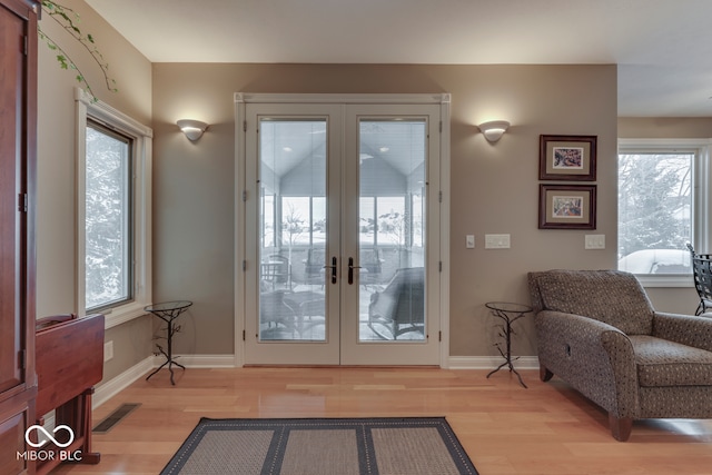 doorway to outside featuring visible vents, baseboards, wood finished floors, and french doors