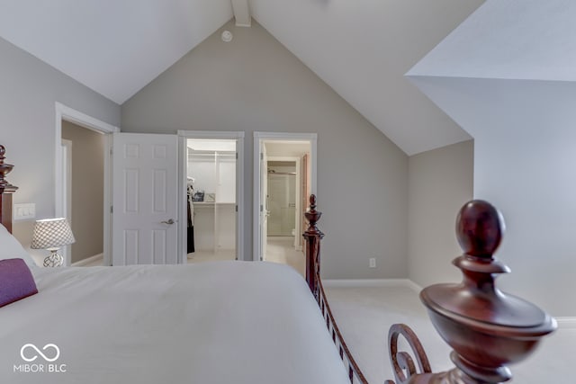 carpeted bedroom featuring ensuite bathroom, a closet, baseboards, a spacious closet, and vaulted ceiling with beams