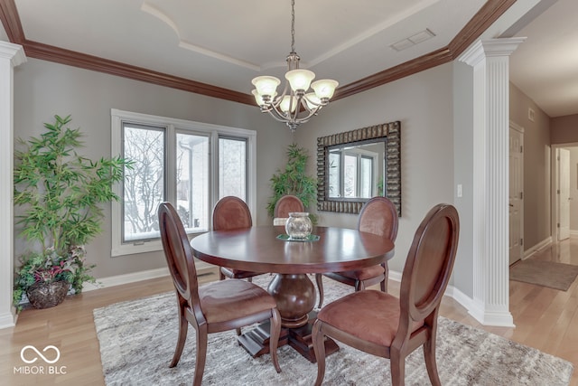 dining space with a healthy amount of sunlight, a raised ceiling, light wood-style flooring, and decorative columns