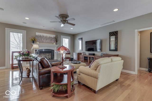 living area with visible vents, recessed lighting, light wood finished floors, a premium fireplace, and baseboards