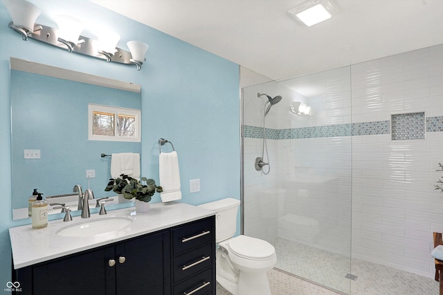 bathroom with toilet, vanity, and a tile shower