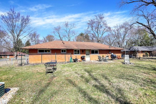 rear view of property featuring a yard, brick siding, a patio area, and fence