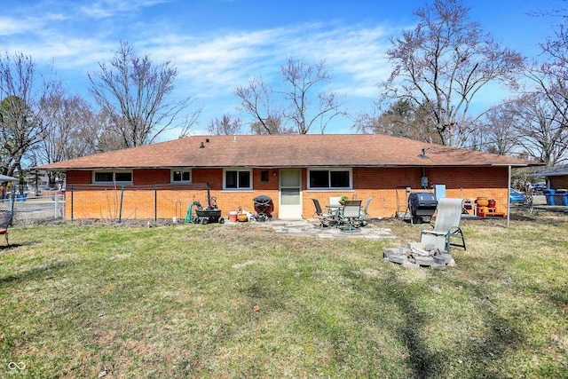 rear view of house with brick siding, a patio, fence, and a lawn