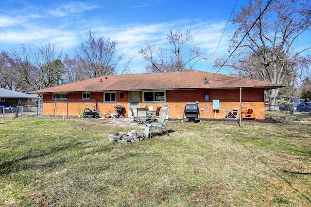 rear view of property featuring brick siding, a yard, and fence