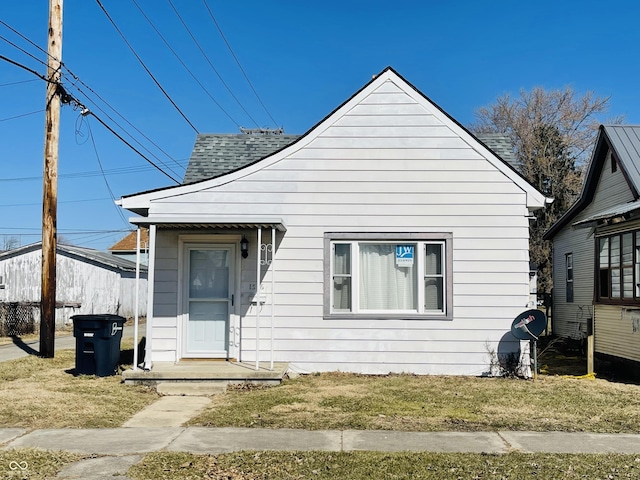 bungalow with a front lawn and roof with shingles