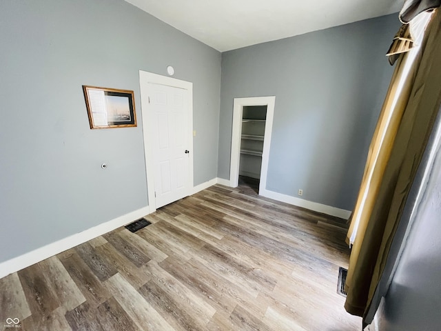 spare room featuring visible vents, baseboards, and wood finished floors