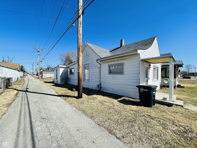 view of property exterior with roof with shingles and a chimney