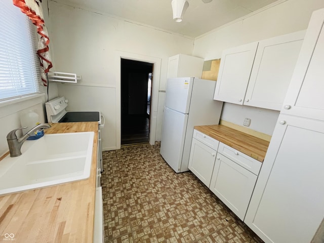 kitchen with white cabinetry, white appliances, butcher block countertops, and a sink