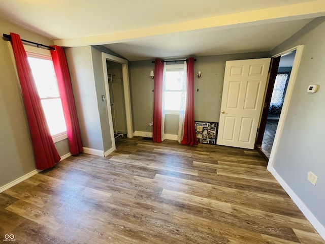 spare room with baseboards, wood finished floors, and vaulted ceiling