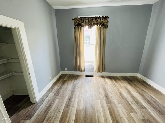 spare room with visible vents, baseboards, and wood finished floors