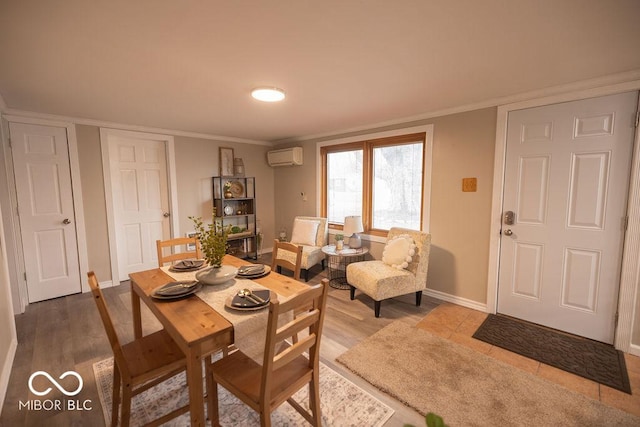 dining area with an AC wall unit, crown molding, baseboards, and wood finished floors