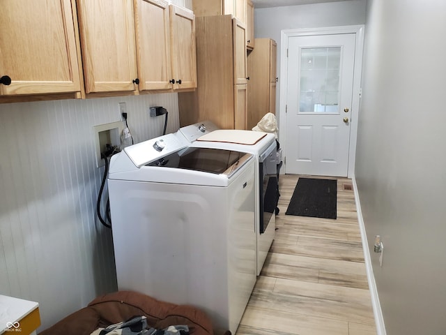 washroom featuring baseboards, cabinet space, and washing machine and clothes dryer