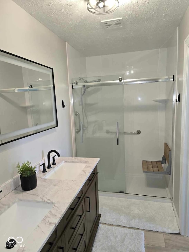 bathroom with double vanity, a stall shower, visible vents, and a sink