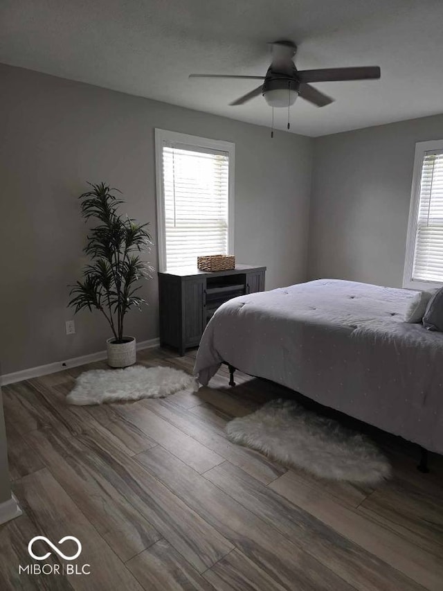 bedroom featuring baseboards, wood finished floors, and a ceiling fan