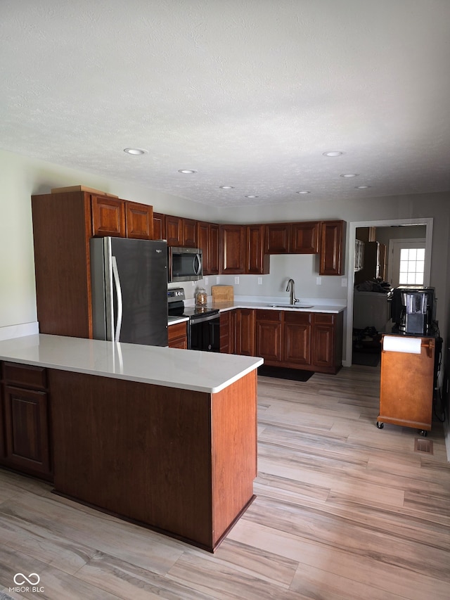 kitchen featuring a sink, stainless steel appliances, a peninsula, and light countertops