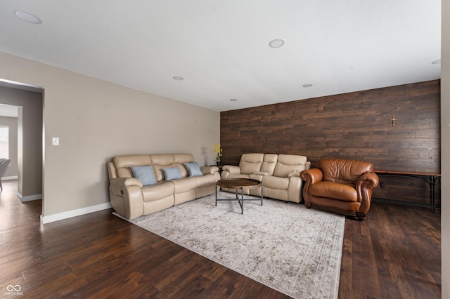 living area featuring an accent wall, wooden walls, wood finished floors, and baseboards