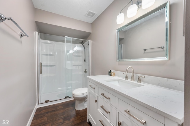 bathroom featuring vanity, wood finished floors, visible vents, a stall shower, and toilet