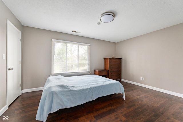 bedroom featuring visible vents, baseboards, and wood finished floors