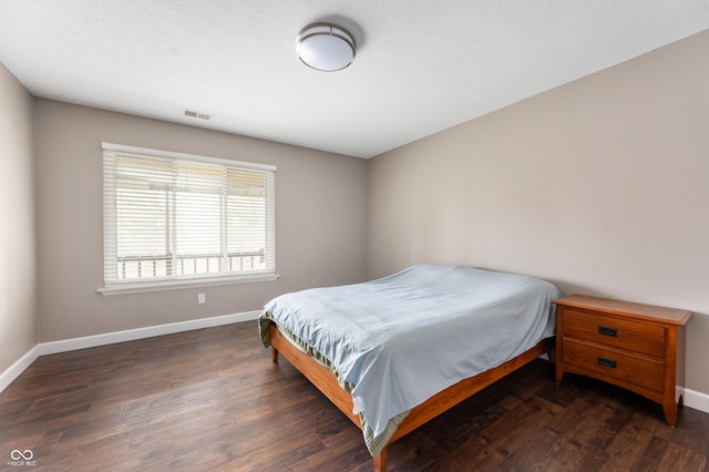 bedroom with wood finished floors, baseboards, and visible vents