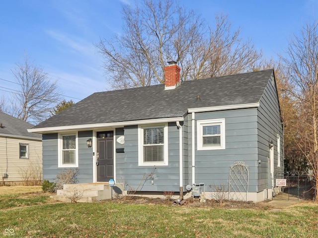 view of front facade with a shingled roof, a chimney, a front lawn, and fence