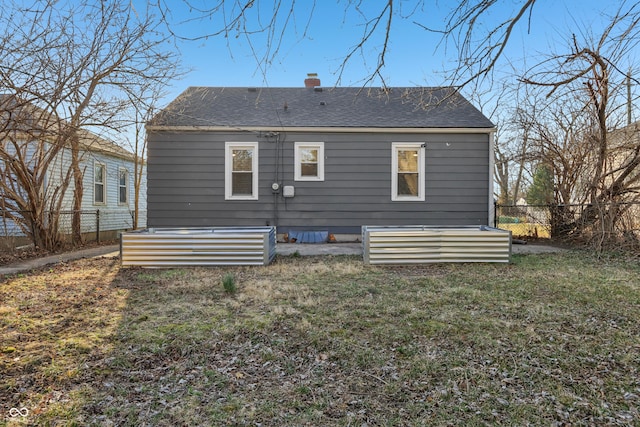 rear view of property with a lawn, a chimney, roof with shingles, and fence