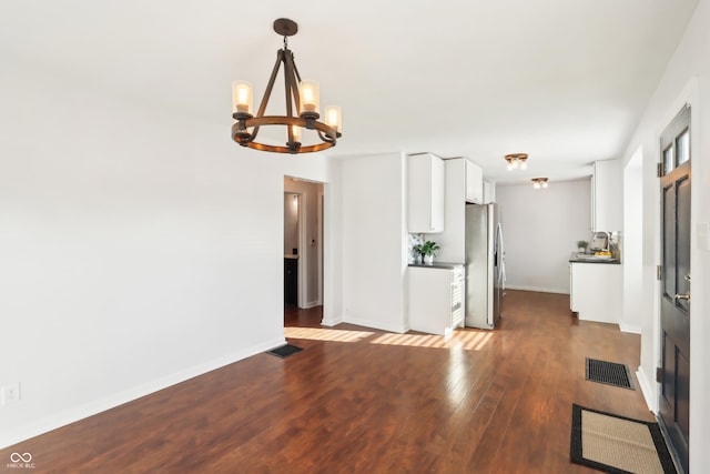 interior space with an inviting chandelier, wood finished floors, visible vents, and baseboards