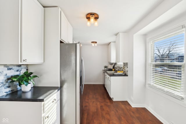 kitchen with baseboards, white cabinetry, dark countertops, and freestanding refrigerator