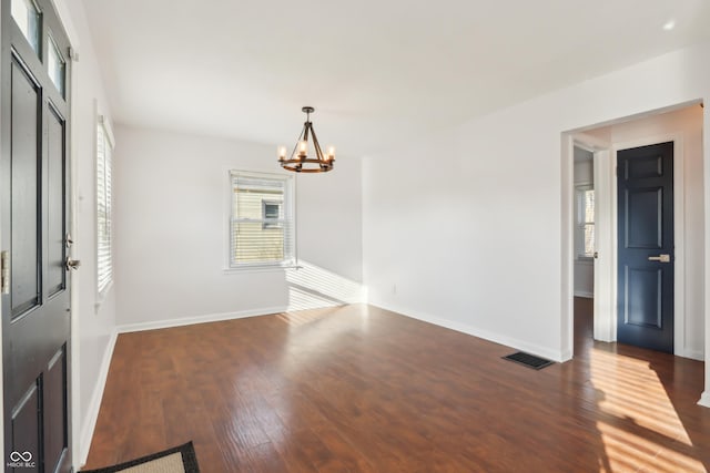 interior space featuring baseboards, wood finished floors, visible vents, and a chandelier