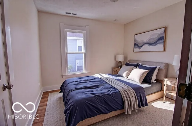 bedroom featuring visible vents, wood finished floors, and baseboards