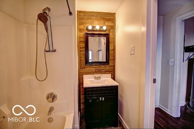 bathroom with shower / bath combination, baseboards, wood walls, and vanity