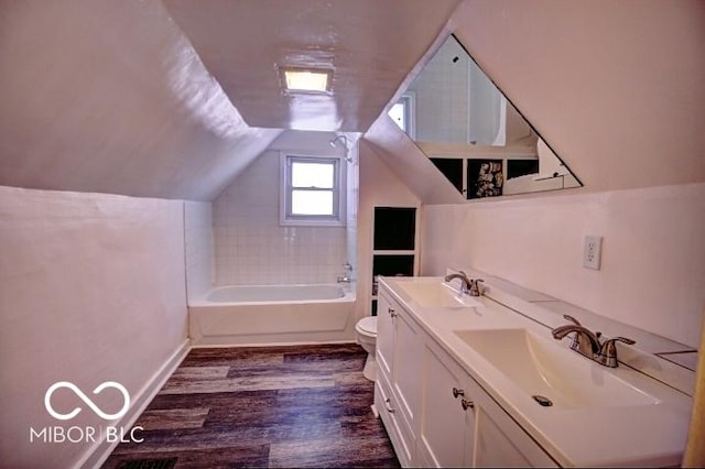 full bathroom featuring toilet, a sink, wood finished floors, double vanity, and lofted ceiling