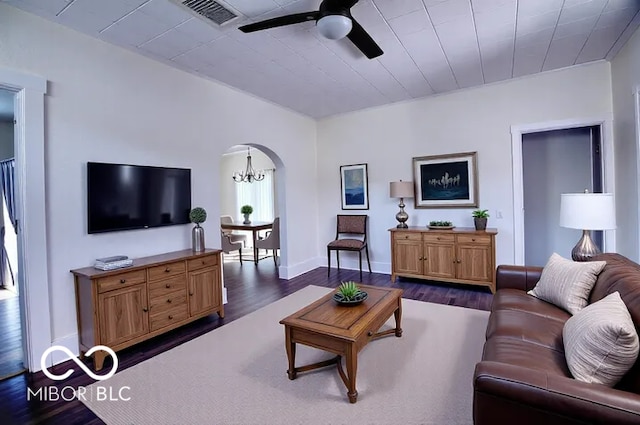 living room featuring visible vents, arched walkways, dark wood-type flooring, and ceiling fan with notable chandelier