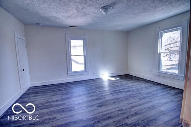 unfurnished room with wood finished floors, baseboards, and a textured ceiling