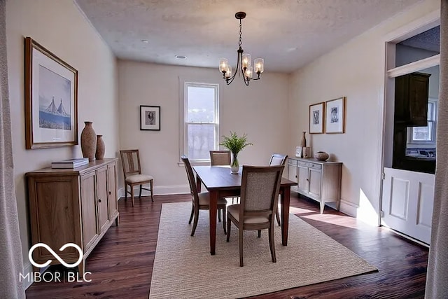 dining room featuring dark wood-type flooring, a notable chandelier, and baseboards