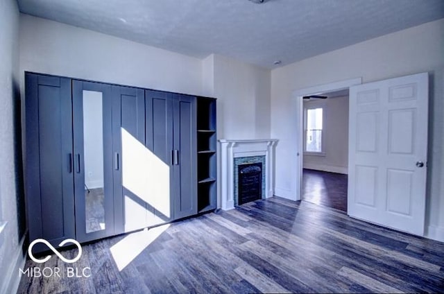 unfurnished living room featuring baseboards, dark wood-type flooring, and a fireplace