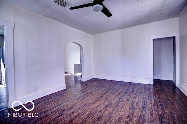 empty room with visible vents, baseboards, wood finished floors, arched walkways, and a ceiling fan