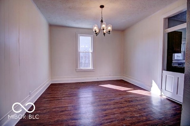 unfurnished room with a notable chandelier, baseboards, a textured ceiling, and wood finished floors