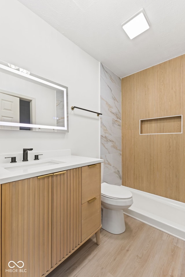 full bath with a shower, toilet, vanity, and wood finished floors