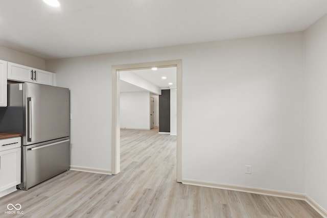 kitchen with white cabinets, light wood-type flooring, freestanding refrigerator, and baseboards