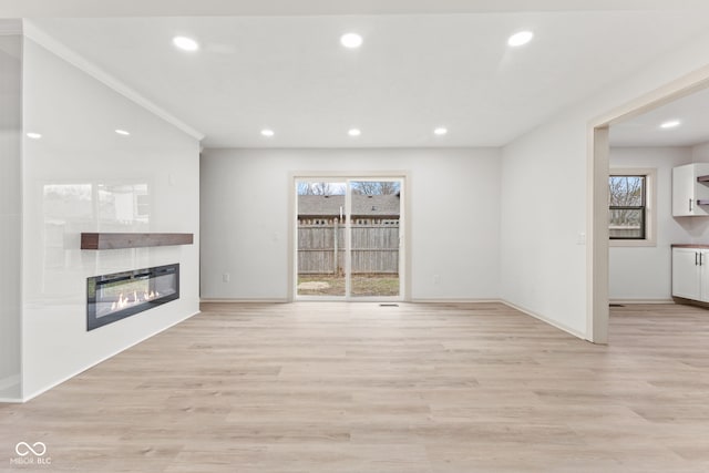 unfurnished living room with a glass covered fireplace, light wood-style flooring, and recessed lighting