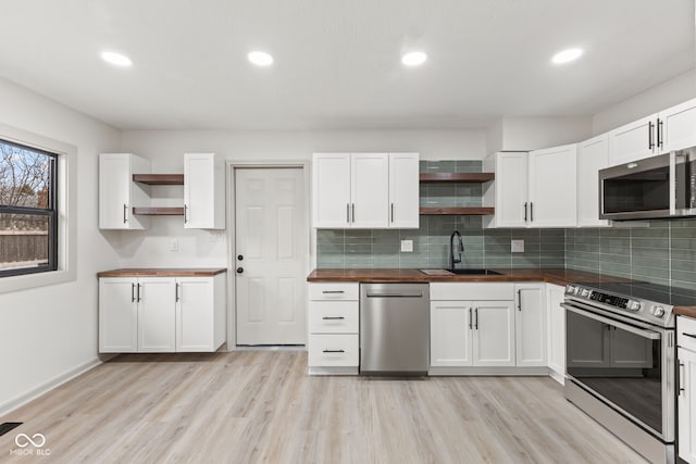 kitchen featuring wooden counters, a sink, appliances with stainless steel finishes, and open shelves